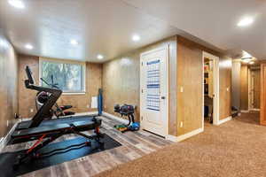 Exercise area with light wood-type flooring and recessed lighting