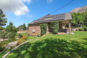 Rear view of house featuring roof mounted solar panels, a yard, and brick siding