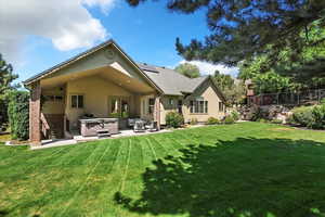 Back of property featuring a hot tub, brick siding, a patio area, solar panels, and stucco siding