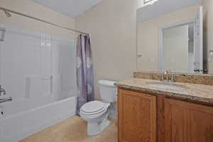 Bathroom with vanity, shower / bath combination with curtain, and light tile patterned floors