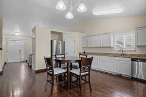 Dining room featuring lofted ceiling, dark wood-style flooring, and hanging lights