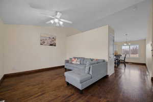 Living room featuring lofted ceiling, dark wood-type flooring, and ceiling fan
