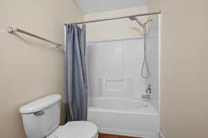 Bathroom featuring toilet and shower / bath combo with shower curtain