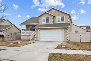 View of front facade with a gate, a shingled roof, concrete driveway, and stucco siding