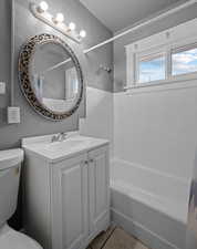Full bathroom featuring a textured wall, vanity, and  shower combination