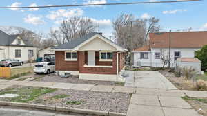 Bungalow with brick siding, an outbuilding, and roof with shingles