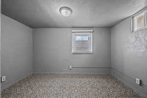 Spare room featuring a textured wall, tile patterned floors, and a textured ceiling