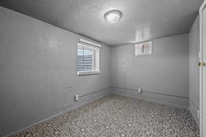 Spare room featuring a textured wall, tile patterned floors, and a textured ceiling