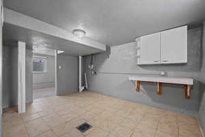 Below grade area featuring a textured ceiling, a textured wall, and light tile patterned floors