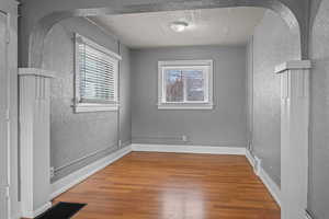 Unfurnished room with a textured wall and light wood-type flooring