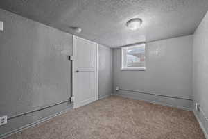 Unfurnished room featuring a textured wall, a textured ceiling, and carpet