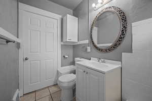 Bathroom with vanity, a textured wall, and light tile patterned floors