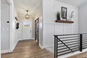 Foyer entrance with light wood-type flooring, a chandelier, and a decorative wall
