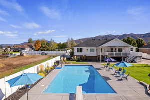 View of pool featuring patio surround, a fenced backyard, a diving board, and a deck with mountain view