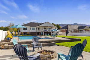 View of pool with patio surround, an outdoor fire pit, a fenced backyard, and a mountain view