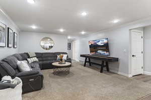 Living area with ornamental molding, light colored carpet, and recessed lighting