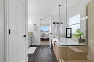 Ensuite bathroom with vanity, a shower stall, a garden tub, and dark tile patterned floors