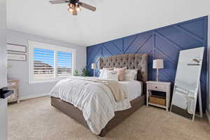 Bedroom featuring a decorative wall, ceiling fan, and light carpet