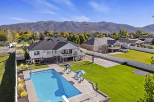 View of pool with patio surround, a residential view, a fenced backyard, a mountain view, and a balcony