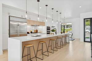 Kitchen featuring a kitchen breakfast bar, a spacious island, light wood finished floors, and dual tone cabinets