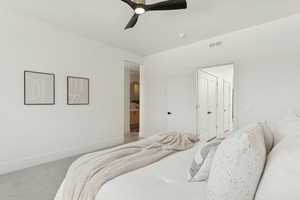 Carpeted bedroom featuring ceiling fan and ensuite bath