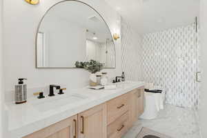 Full bathroom with double vanity, a soaking tub, a shower stall, and light marble finish flooring