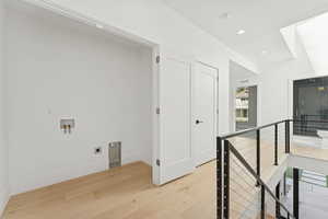 Hall featuring an upstairs landing, light wood finished floors, and recessed lighting