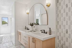 Full bath featuring double vanity, light marble finish floors, a shower with curtain, and a textured ceiling