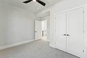 Unfurnished bedroom featuring light colored carpet, ceiling fan, and a closet