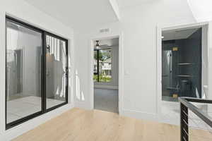 Full bathroom with light wood-style flooring, a shower stall, vanity, and a ceiling fan