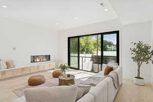 Living area featuring light wood finished floors, a glass covered fireplace, and recessed lighting