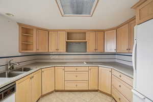 Kitchen featuring light wood finish cabinetry, white appliances, light tile patterned floors, backsplash, and open shelves