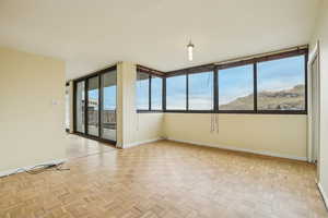 Spare room featuring parquet flooring and baseboards