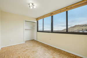 Unfurnished bedroom featuring parquet floors, a mountain view, and a closet
