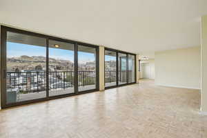 Empty room featuring floor to ceiling windows, a mountain view, and parquet flooring