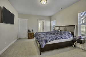 Bedroom featuring light colored carpet and connected bathroom