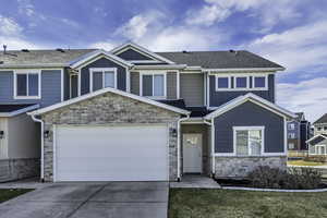 Craftsman-style home with board and batten siding, stone siding, concrete driveway, roof with shingles, and an attached garage