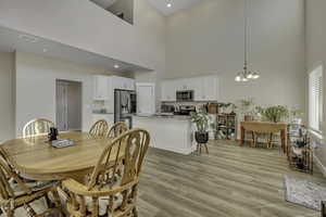 Dining space with light wood finished floors, a chandelier, and a high ceiling