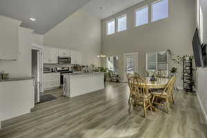 Dining space featuring light wood-style flooring, a high ceiling, and suspended lighting