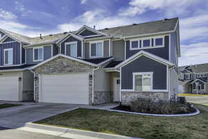 Craftsman-style home with stone siding, board and batten siding, concrete driveway, a front yard, and a garage