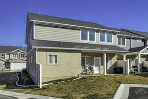 Back of house featuring a covered patio area, extra guest parking, stucco siding, with large grass yard on three sides