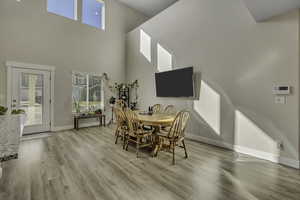 Dining room featuring healthy amount of natural light, light wood-style flooring, and a high ceiling