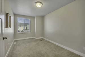 Spare room with light carpet and a textured ceiling