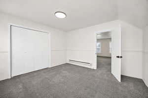 Unfurnished bedroom with carpet flooring, a baseboard radiator, and a closet