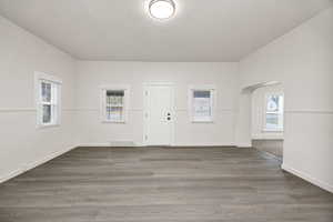 Foyer featuring arched walkways, dark wood finished floors, and a textured ceiling