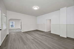 Unfurnished room featuring wood finished floors and arched walkways