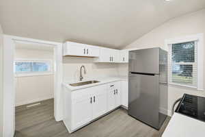 Kitchen with freestanding refrigerator, plenty of natural light, white cabinets, and light wood-type flooring