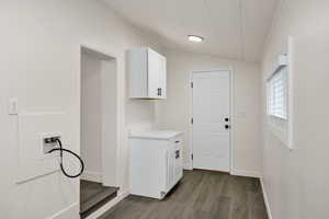 Laundry area featuring cabinet space, washer hookup, dark wood-style flooring, and vaulted ceiling