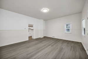 Empty room featuring dark wood-type flooring and baseboards