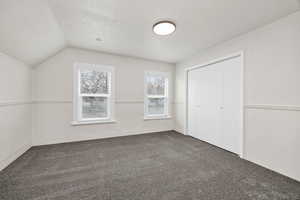 Unfurnished bedroom with dark carpet and a closet